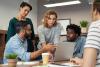 stock image of team working together around computer screen